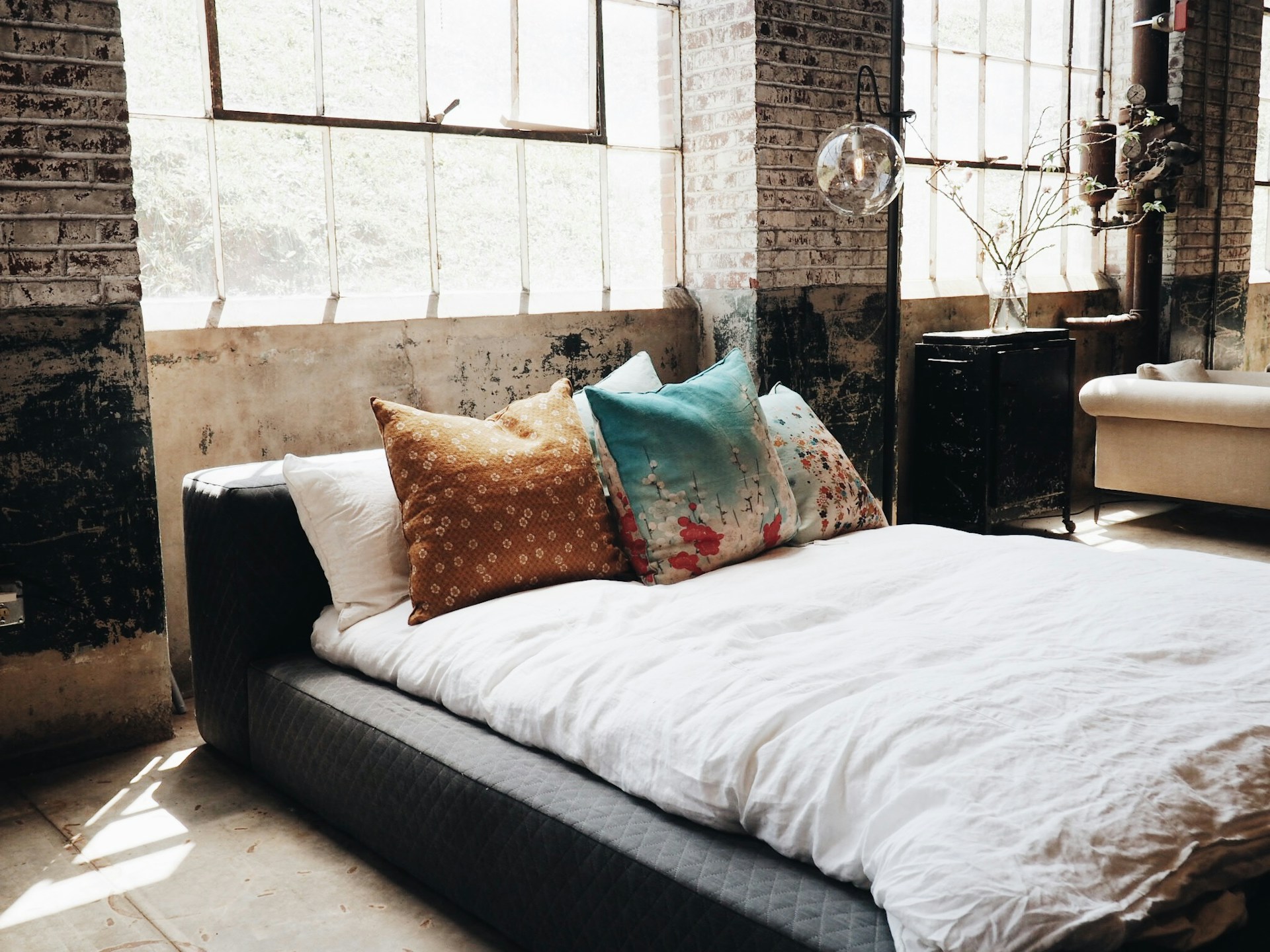 Modern loft bedroom with large windows and pillows