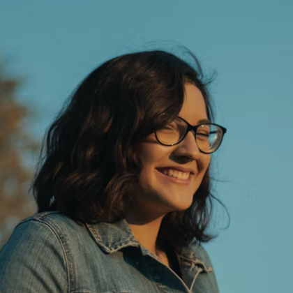 Smiling woman with glasses under blue sky